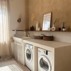 a washer and dryer in a room with beige walls, white tile flooring