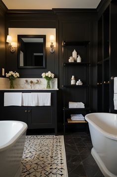 a white bath tub sitting next to a sink in a bathroom under a mirror and lights