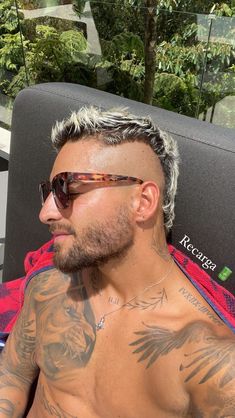 a man with tattoos on his chest wearing sunglasses