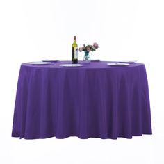 a purple table cloth with two wine glasses and a bottle sitting on top of it