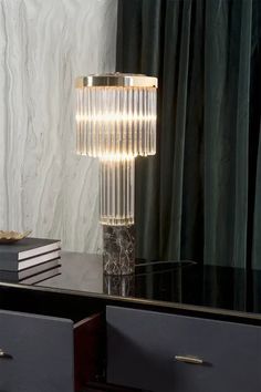 a lamp that is on top of a table next to some books and a vase