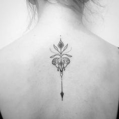 the back of a woman's neck with an arrow and flower tattoo on it