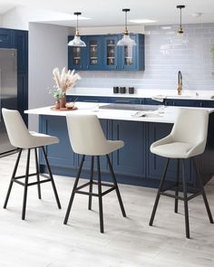 a kitchen with blue cabinets and white counter tops, three stools in front of the island