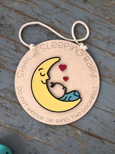 a wooden hanging sign with a sleeping baby on the moon