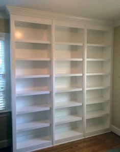 an empty white bookcase in the corner of a room