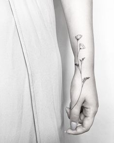 a person with a flower tattoo on their left arm and the other hand is holding an object