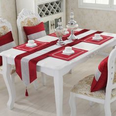 a dining room table set with red and white placemats, silver candlesticks and napkins