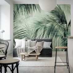 a living room filled with furniture and wallpaper covered in green palm leaf print on the walls