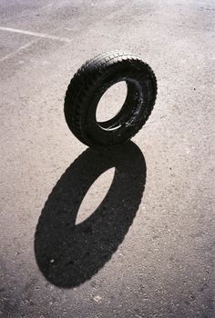 an old tire laying on the ground with its shadow cast by it's side