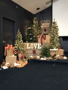 christmas trees and presents are on display in front of a sign that says joy love