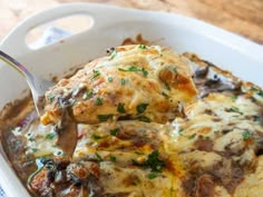 a close up of a spoon in a casserole dish with meat and cheese