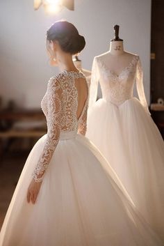 a woman in a wedding dress standing next to two mannequins wearing long sleeves