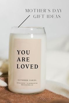 a candle with the words you are loved printed on it, sitting on a blanket