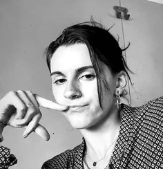 a black and white photo of a woman holding something up to her mouth with both hands