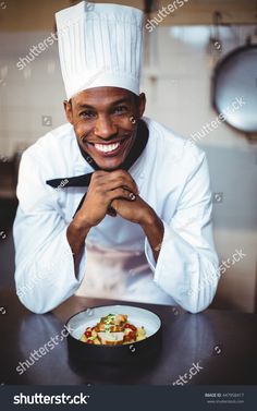 a smiling chef posing with his plate of food in front of him on the table