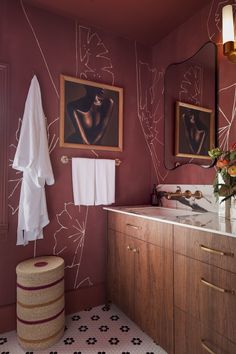 a bathroom with red walls and artwork on the wall