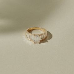 a gold ring with a baguette cut diamond set in the center on a white surface