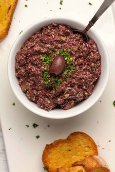 a white bowl filled with food next to bread