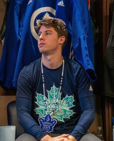 a young man sitting in front of a hockey jersey