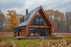 a small house with a metal roof in the middle of some grass and autumn trees