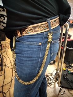 a person wearing a gold chain belt and jeans