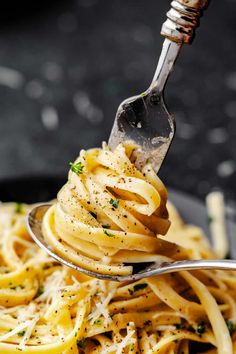 a fork full of pasta with parmesan cheese and herbs on it, being lifted from a bowl