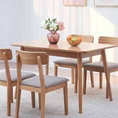 a wooden table with four chairs and a bowl of fruit on top of the table