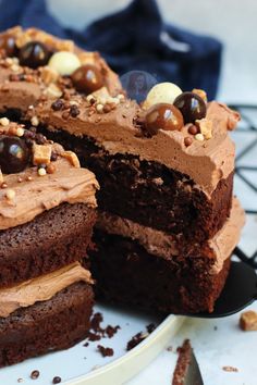 a cake with chocolate frosting and nuts is cut in half on a plate next to a knife