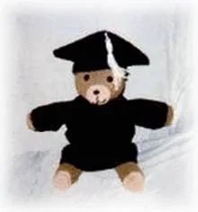 a teddy bear dressed in a black graduation gown and cap, sitting on a white sheet