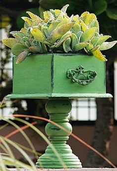 a green planter with succulents in it sitting on top of a table