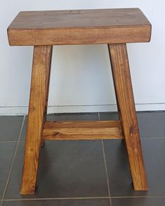 a wooden stool sitting on top of a tiled floor