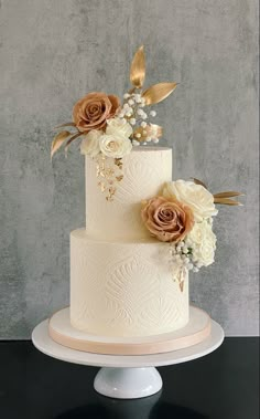 a three tiered wedding cake with flowers and leaves on the top, sitting on a pedestal