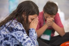 two children sitting on the ground with their hands covering their faces