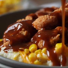 someone is pouring sauce on some food in a bowl with corn and mashed potatoes