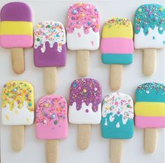 colorful ice cream and sprinkles are arranged on top of popsicles