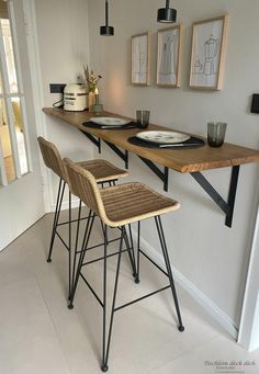 three bar stools are lined up against the wall with plates on them and cups in front of them