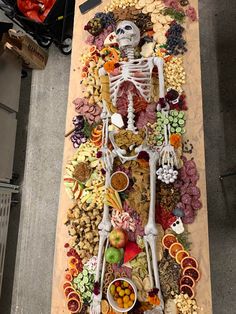 a table topped with a skeleton and lots of different types of food on top of it