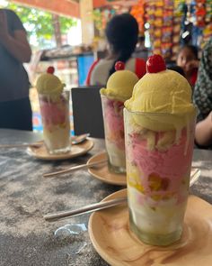 two desserts with ice cream and cherries on top are sitting on the table