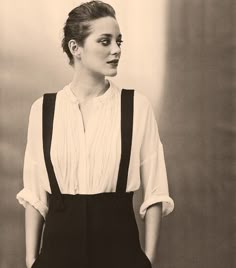 a black and white photo of a woman in overalls with her hands on her hips