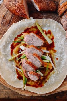 a tortilla filled with meat and vegetables on top of a wooden cutting board