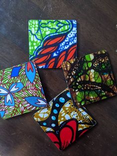 four colorful coasters sitting on top of a wooden table