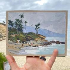 a hand holding up a piece of paper with an image of people on the beach