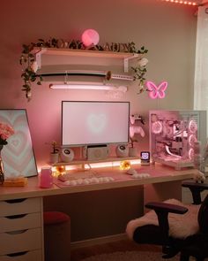 a desk with a monitor, keyboard and other items on it in front of a window