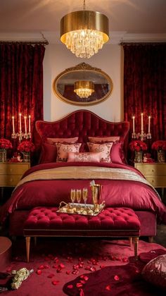 a bedroom with red bedding, chandelier and rose petals on the floor