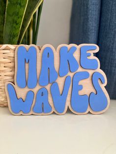 a wooden sign that says make waves next to a potted plant