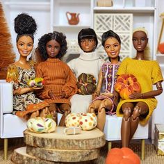 four dolls sitting on a white couch in front of a coffee table with pumpkins