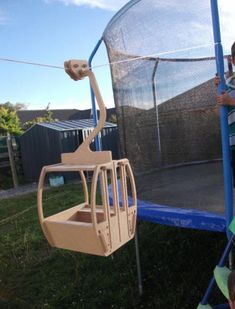 two children playing in a trampoline with a net on the back and one child holding onto it