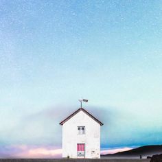 a small white house sitting on top of a hill under a blue sky filled with stars