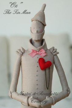 a small doll with a red heart on it's chest and an inscription in the background