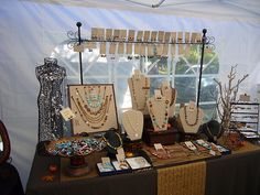 an assortment of jewelry displayed on a table in front of a white tent with windows